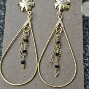 Détail des perles noires sur boucles d’oreilles dorées
