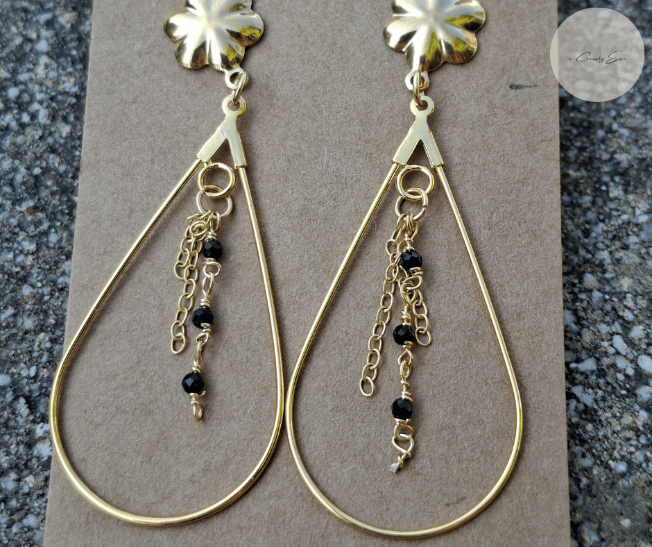 Détail des perles noires sur boucles d’oreilles dorées